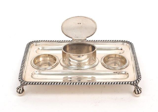 A George V silver inkstand, Birmingham, 1926, John Collard Vickery, the rectangular stand raised on four claw and ball feet to gadrooned border, the centre with oval compartment with hinged cover, inkwells deficient, 14.2 x 21cm long, approx...