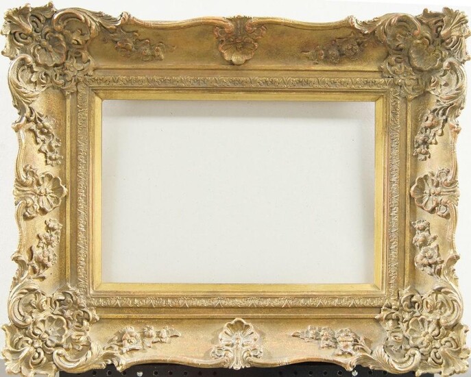 A Gilded Composition Louis XV Style Swept Frame, late 20th century, with cavetto sight, stiff leaf ogee course, sanded frieze, the plain hollow with foliate and flower head scrollwork, shell and cartouche centres and corners, schematic demi-fleur...