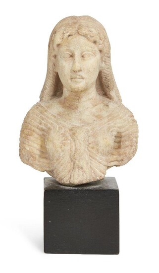 A Roman marble bust of Isis, circa 1st Century A.D., the wavy hair with central parting, falling in eight tight ringlets below the fillet, her face with large almond-shaped eyes and full lips, wearing a finely pleated close-fitting robe typically...