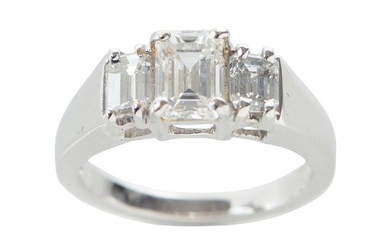 A THREE STONE DIAMOND RING IN 18CT WHITE GOLD, CENTRALLY SET WITH AN EMERALD CUT DIAMOND OF 1.30CTS FLANKED BY FURTHER EMERALD CUT D...