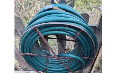 A large garden hose pipe on a metal wall hanging frame with ...