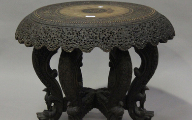 A late 19th/early 20th century Burmese hardwood revolving occasional table, profusely carved with fo