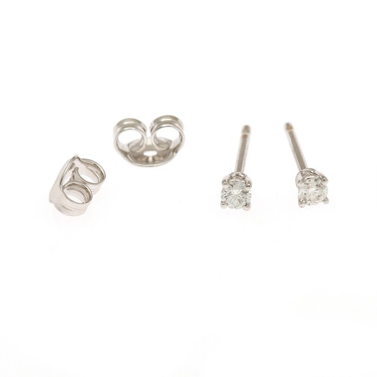 A pair of diamond solitaire ear studs each set with a brilliant-cut diamond, totalling app. 0.18 ct., mounted in 18k rhodium plated gold. F-G/VS. (2)