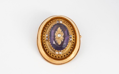 Broche ovale en or jaune (750) centrée d'un verre violet ovale facetté orné d'une fleur...