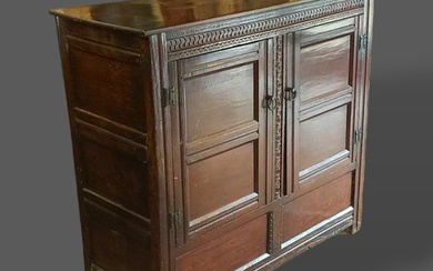 A George III oak bacon cupboard with a carved frieze above t...