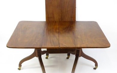 A Georgian mahogany double pedestal dining table raised on reeded legs terminating in brass caps and