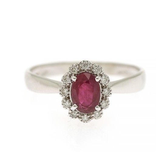 A ruby and diamond ring set with an oval-cut ruby encircled by numerous brilliant-cut diamonds, mounted in 18k white gold. Size 55.