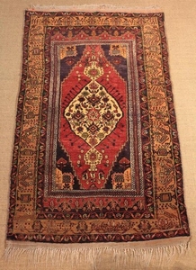 An Antique Caucasian Tribal Rug. The central medallion with north south pendants on a claret ground within a light & dark brown banded border, 46 in x 80 in (117 cm x 203 cm).