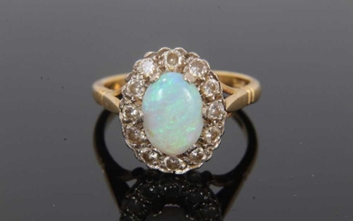 Opal and diamond cluster ring with an oval cabochon opal measuring approximately 8.9mm x 6.4mm x 2.1mm, surrounded by a border of twelve brilliant cut diamonds on 18ct gold shank. Estimated total d...