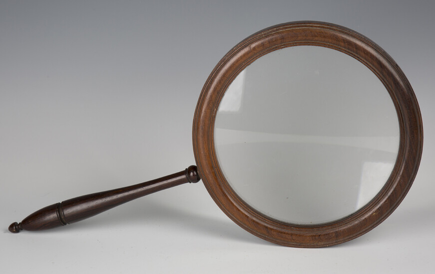 A 19th century rosewood gallery glass, the large circular frame supporting a glass lens, length 45.5