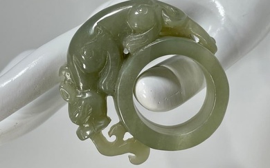 A CHINESE QING DYNASTY CELADON JADE RING WITH A HIGH RELIEF DRAGON, 18TH CENTURY OR EARLIER
