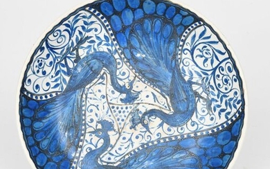 A John Pearson pottery shallow bowl, painted to the well with three peacock birds before scrolling foliage, in blue outlined in black on a white ground, painted JP monogram, hairline crack to rim, 26.5cm. diam.