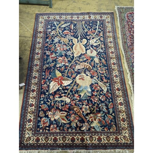 A Kirman blue ground rug woven with birds amongst flowering ...