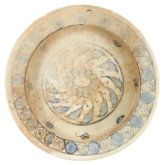 A Miletus ware blue and white pottery bowl, Turkey, 15th century, underglaze painted to centre well with central flower head and revolving leaf pattern, the rim with spiral and circle alternating motifs, 18.2cm. diam. Miletus ware was superseded in...