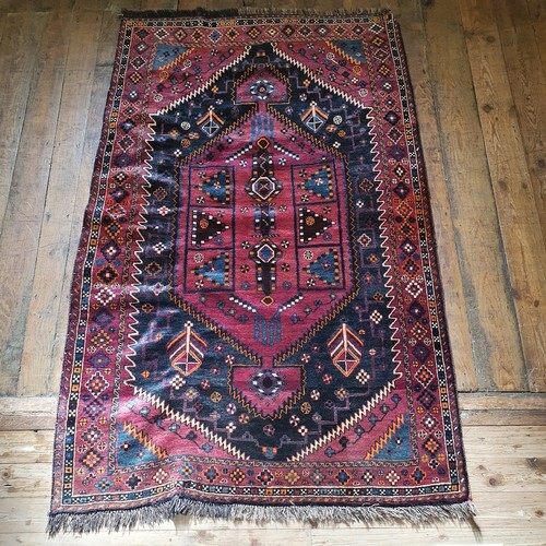 A Persian red ground rug, with multiple borders, centre with...