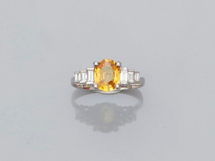 White gold ring, 750 MM, set with an oval yellow sapphire weighing 1.55 carat and set with six stepped baguette-cut diamonds, 17 x 9 mm, size: 55, weight: 3.5gr. rough.