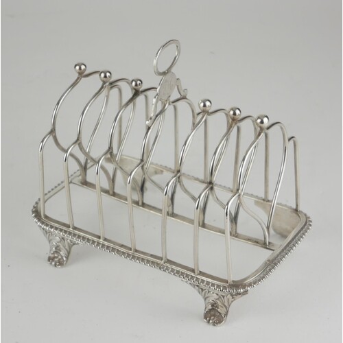 A GEORGE III SILVER TOASTRACK Having an oval form carry hand...