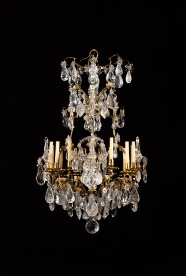 A Louis XV style varnished-bronze, rock crystal and glass chandelier | Lustre à douze lumières en bronze verni, cristal de roche et verre de style Louis XV