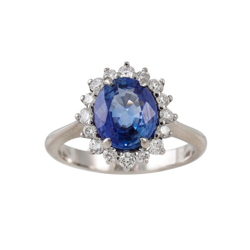 A SAPPHIRE AND DIAMOND CLUSTER RING, of oval from, mounted i...