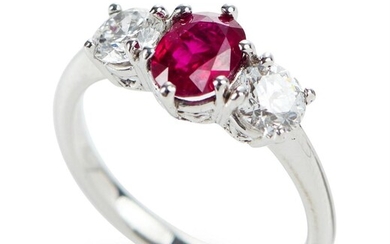 A THREE STONE RUBY AND DIAMOND RING IN 18CT WHITE GOLD, FEATURING AN OVAL CUT RUBY OF 1.10CTS, SHOULDERED BY ROUND BRILLIANT CUT DIA...