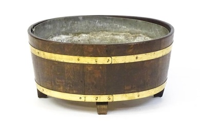 A late Georgian oak wine cooler / cellarette with a coopered and brass strapped frame and raised on