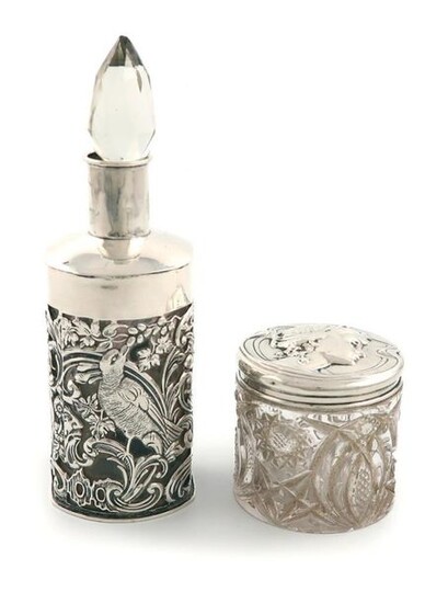 An Edwardian Art Nouveau silver-mounted toilet jar, by William Hutton and Sons, Birmingham 1904, the cover embossed with a female head, glass body, plus a silver-mounted scent bottle, by William Comyns, London 1899. (2)