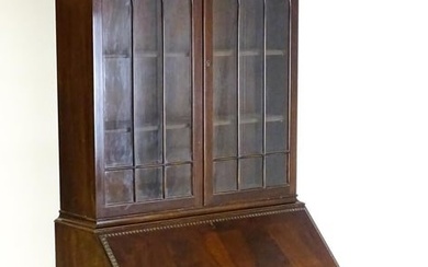 An early 20thC mahogany bureau bookcase with a carved cornice above two astragal glazed doors and a