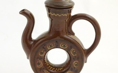 An slipware lidded wine ewer with a ring shaped body on