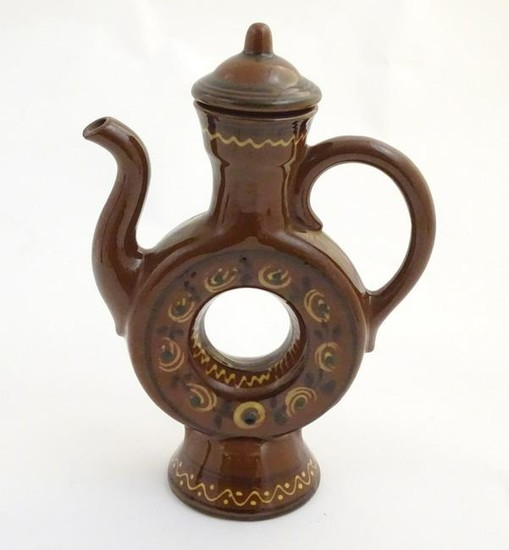 An slipware lidded wine ewer with a ring shaped body on