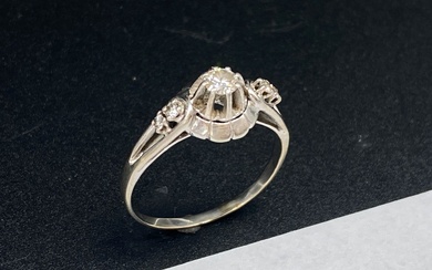 Bague en or gris 18K (750 millièmes) ajouré, centré d'un diamant taillé en brillant calibrant...