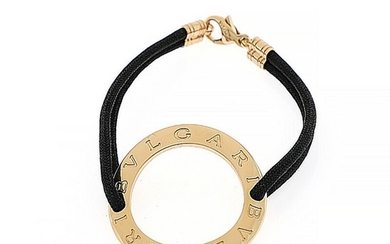 Bulgari: A bracelet of 18k gold and black string. L. app. 16 cm. Diam. front app. 3.5 cm.