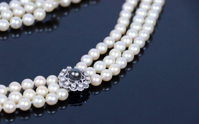 Collier de trois rangs de perles de culture japonaises Akoia en chute, le fermoir en or gris orné d'une perle de Tahiti dans un entourage de pierres blanches.