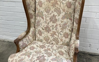 Louis XV Style Probably Walnut Wingback Armchair, fully upholstered in a cream fabric with floral arabesques & on cabriole legs (h:1...