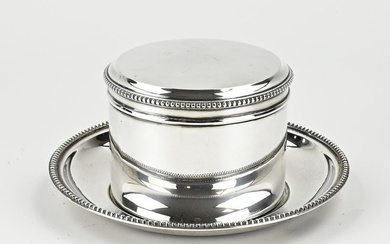 Silver biscuit tin on saucer