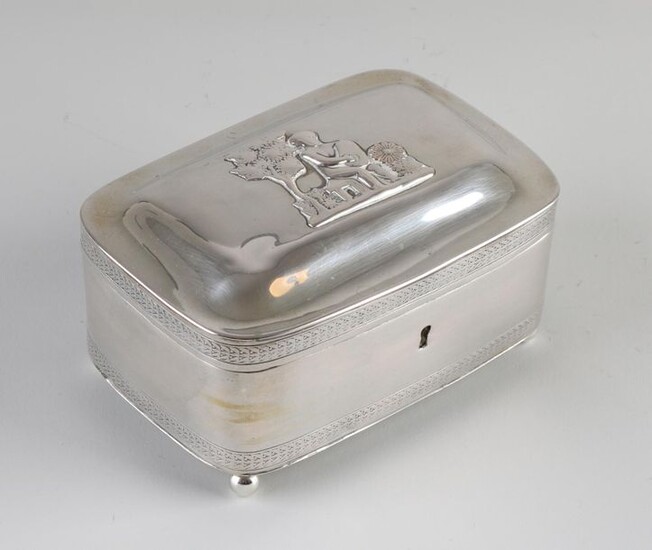 Silver tea box, rectangular model with rounded corners and 2 edged edges, placed on 4 ball legs. On top of the hinged lid is a soldered image of a figure with a harp outside on a bench, partly worn. The box has a lock. Approved with a label for...