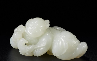 A white jade carving of a recumbent boy holding a bird