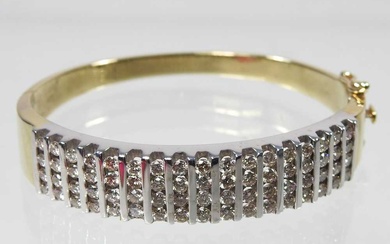A 14 carat gold and diamond bangle, of hinged design,...