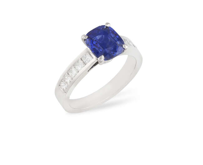 A SAPPHIRE AND DIAMOND RING The cushion-shaped sapphire...