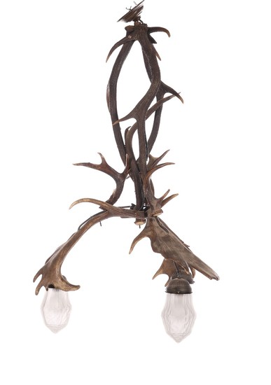A hanging lamp of antlers from stag and fallow deer, three sockets with glass shades. Early 20th century. H. 118. Diam. 68 cm.