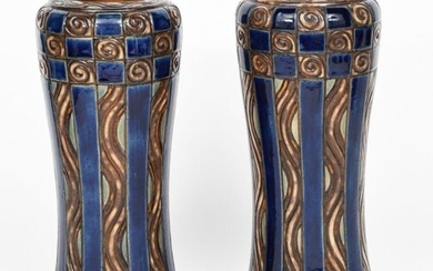 A near pair of Royal Doulton stoneware vases, slender waisted cylindrical form with inverted top rim, incised and painted with geometric panels in blue and brown impressed marks and incised EB monogram, 34.5cm. high (2)