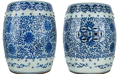 A pair of Chinese blue and white garden stools, late 19th century, each in the shape of a barrel, painted to the sides with scrolling lotus foliage pierced with two conjoint coins in between two bands of rounded studs in relief, the top similarly...