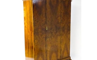 An Art Deco style walnut wardrobe with a shaped cornice abov...