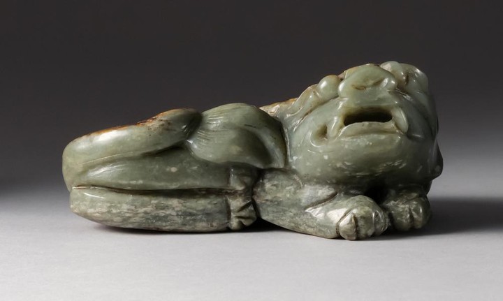 CHINESE CELADON AND RUSSET JADE CARVING In the form of a reclining guardian lion. Length 5".