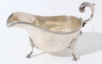 George V silver sauce boat of helmet form with gadrooned borders and scroll handle, raised on three hoof feet, retailed by Tiffany & Co (London 1934)