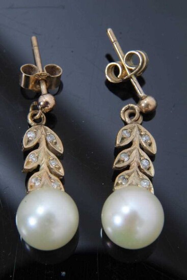 Pair of cultured pearl and diamond pendant earrings with a 7mm cultured pearl suspended from stylized diamond foliage in 9ct gold setting. 21mm