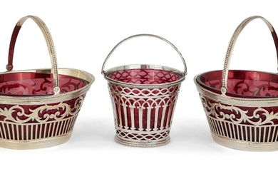 Three Victorian silver sweetmeat baskets with red glass liners, comprising: a pair of oval baskets, London, c.1887, Daniel & John Wellby, both very faintly gilded, 11.2 cm long, 5.1cm high, and an earlier round example, London, c.1882, Rosenthal...