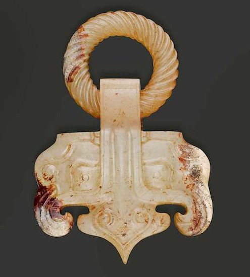 A PALE CELADON AND RUSSET JADE BELT HOOK IN THE SHAPE OF A RINGED TAOTIE-MASK.