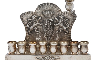 A Polish Hanukkah lamp by M. Blizinski, stamped 925, late 19th/early 20th century, with baluster lamps and servant lamp, the backplate embossed with rampant lions flanking crowned plaque with Hebrew lettering, 18.6cm wide, approx. 15cm high (inc...