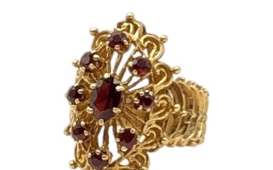 A VINTAGE YELLOW METAL AND GARNET CLUSTER RING Having an ova...
