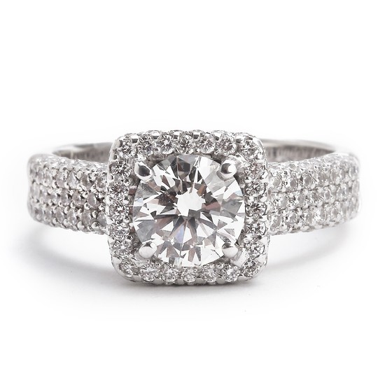 A diamond ring set with a brilliant-cut diamond weighing app. 1.10 ct. encircled and flanked by numerous brilliant-cut diamonds, mounted in platinum. H/VS.